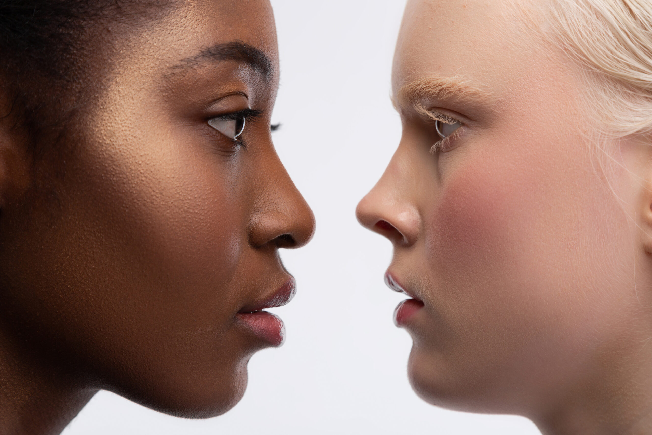 Looking into eyes. Two young multinational women with different skin color looking into eyes of each other