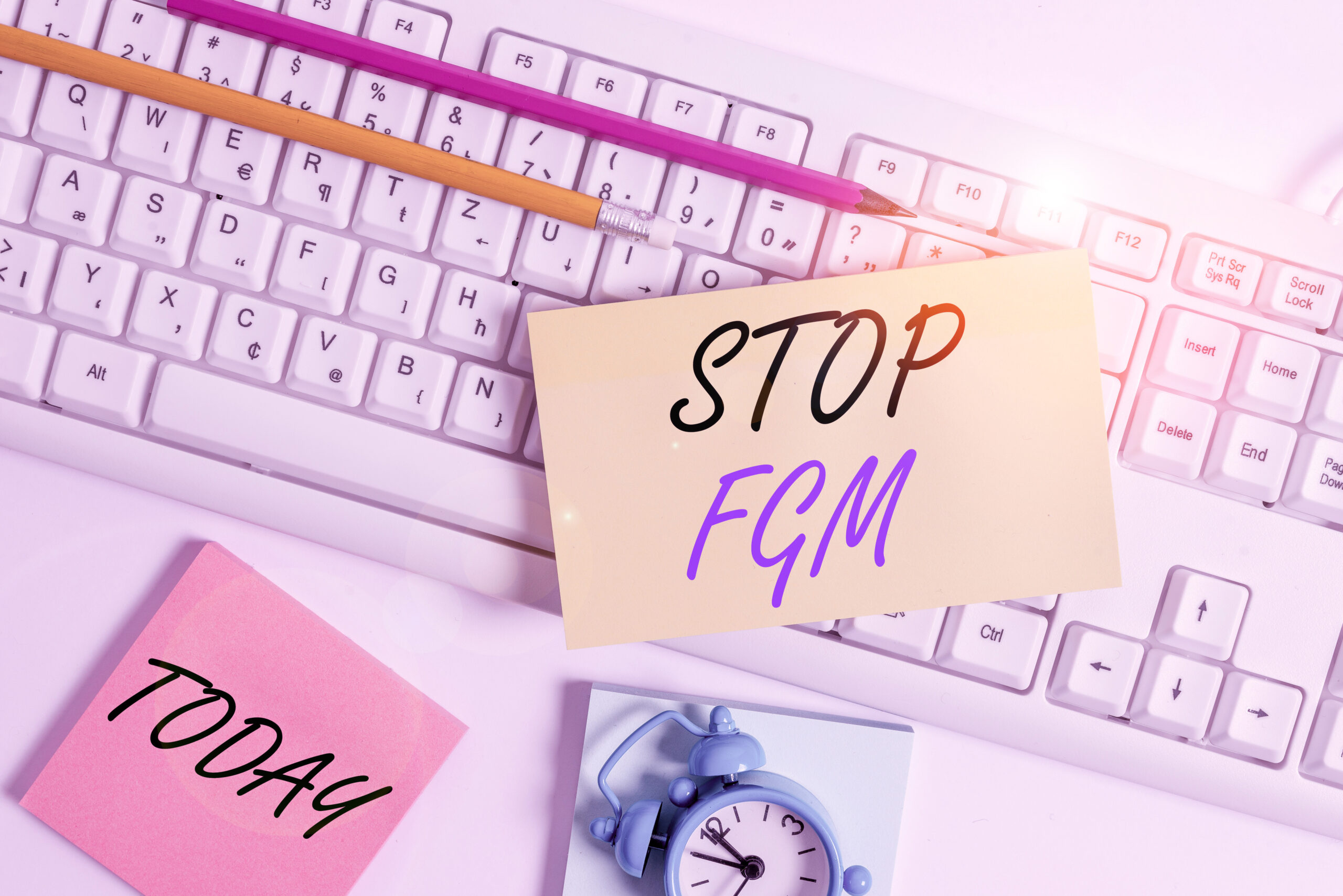 Text sign showing Stop Fgm. Business photo showcasing Put an end or stop on genital cutting and circumcision Flat lay above empty note paper on the pc keyboard pencils and clock