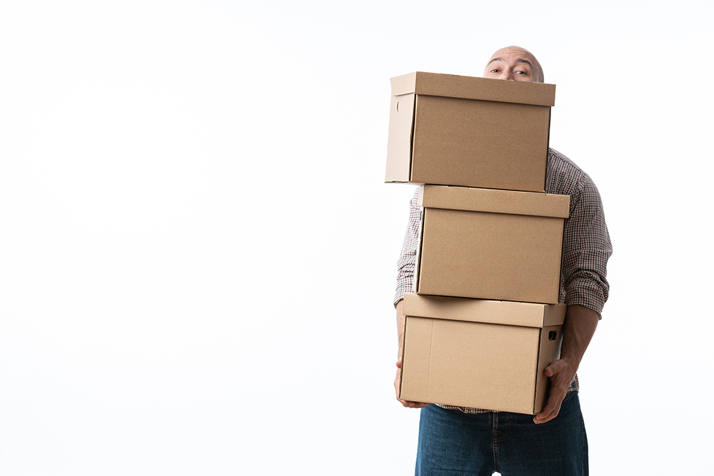 Portrait of a handsome young man holding card boxes, isolated on white